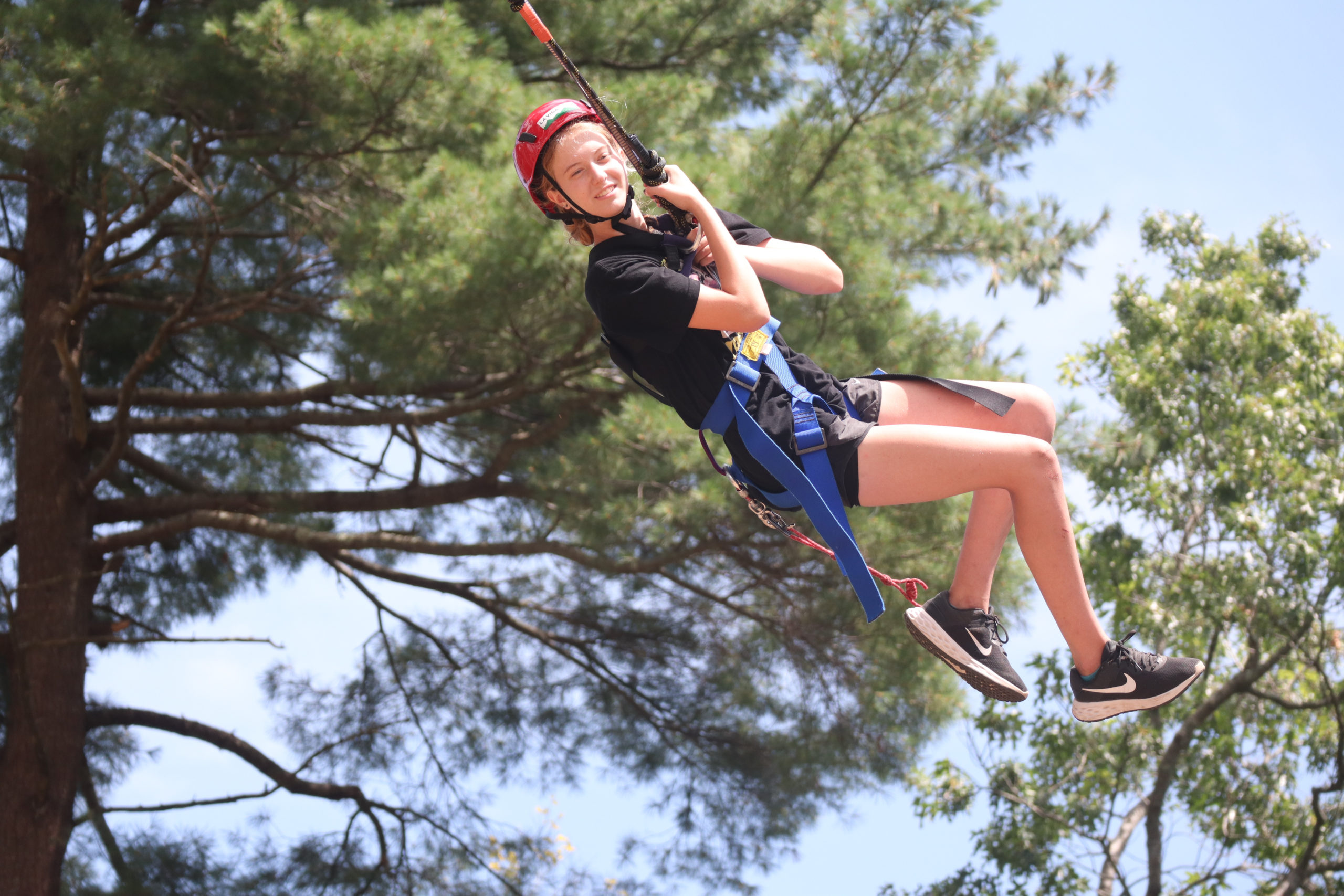 A girl swinging from the Giant Swing at Adventure Camp. 