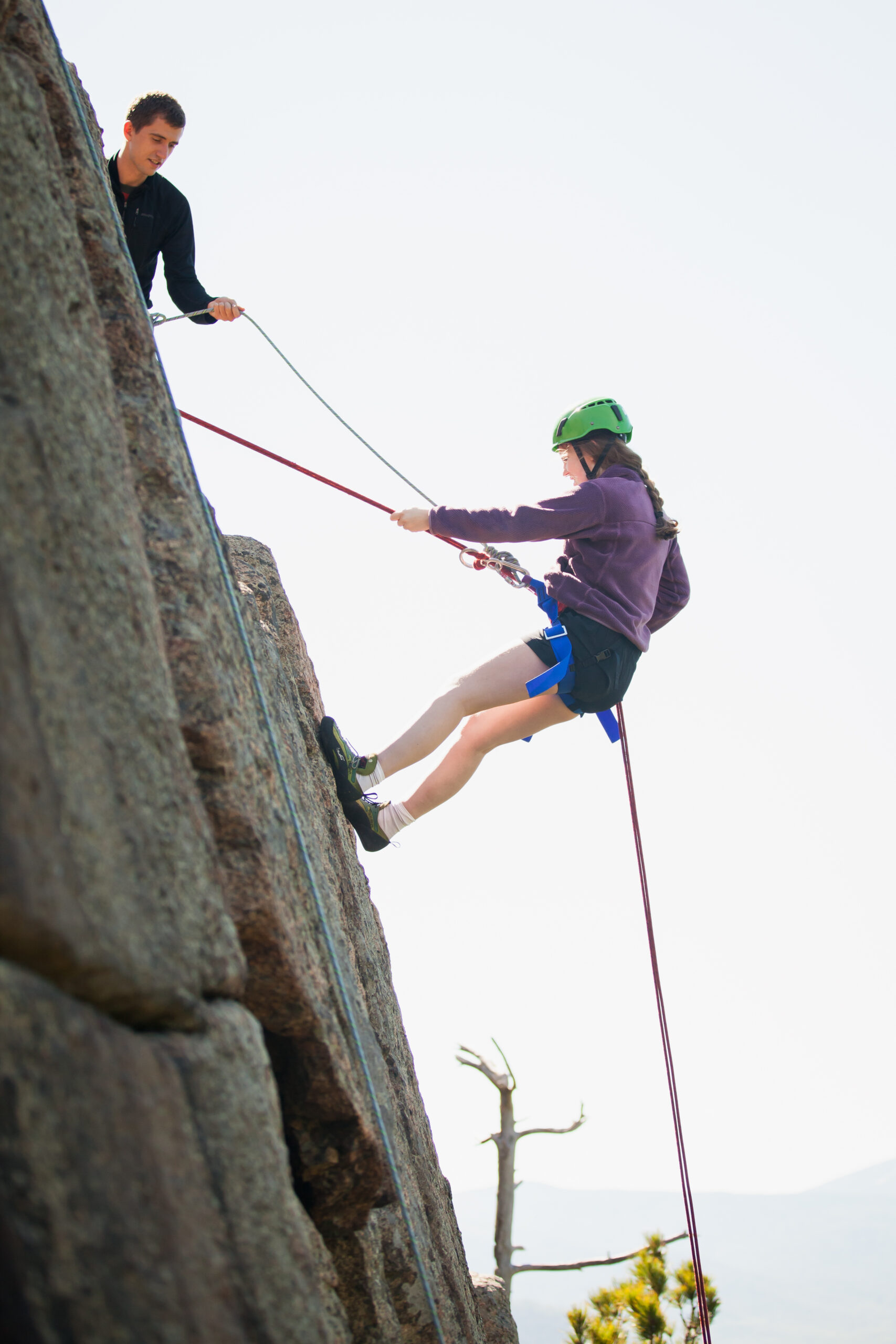 a student rappelling off of a rock face.