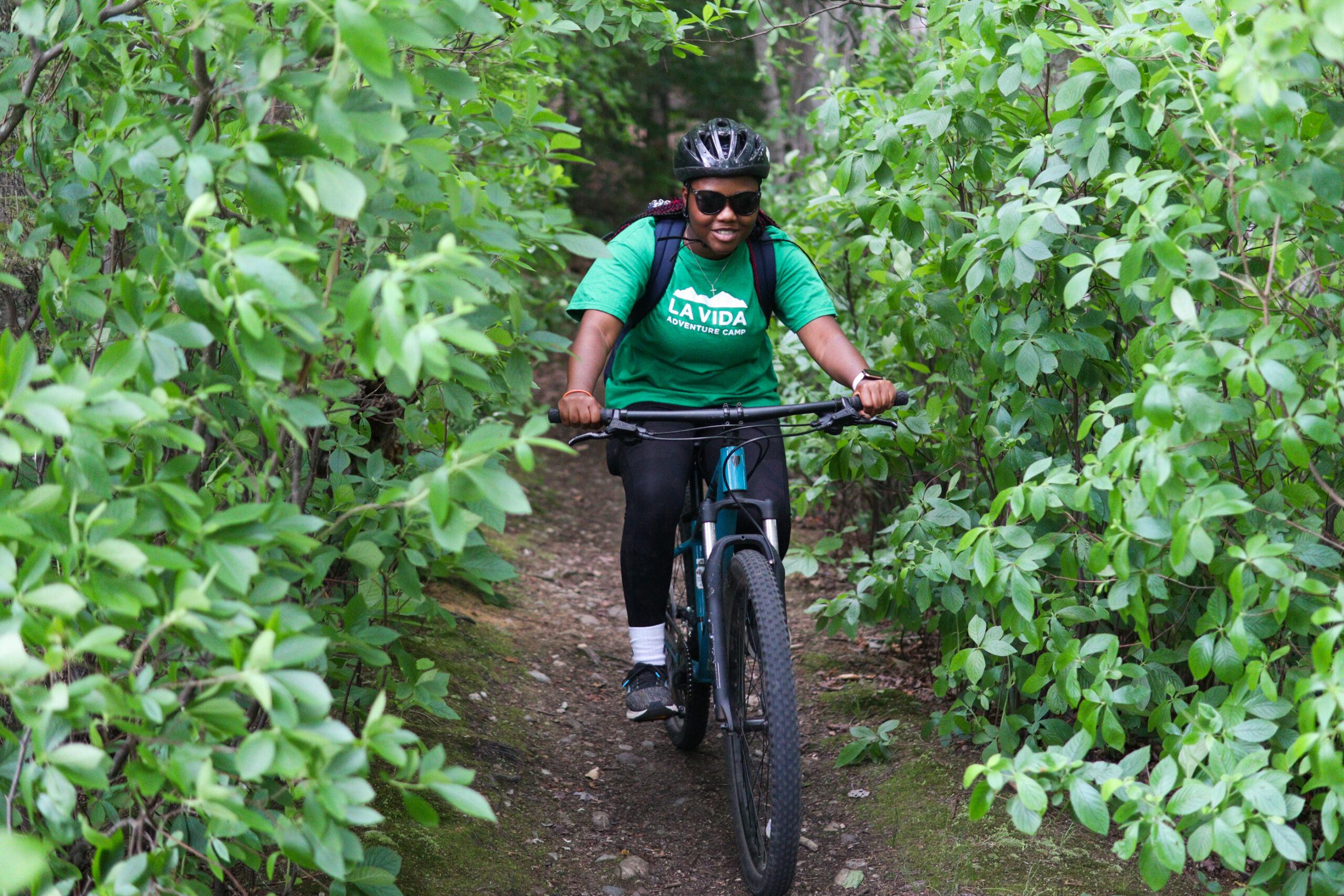 A girl mountain biking in the woods at Adventure Camp. 